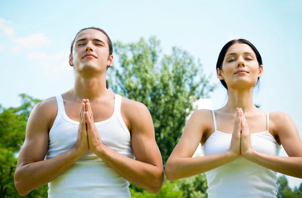 Pareja joven meditando, al aire libre — Foto de Stock