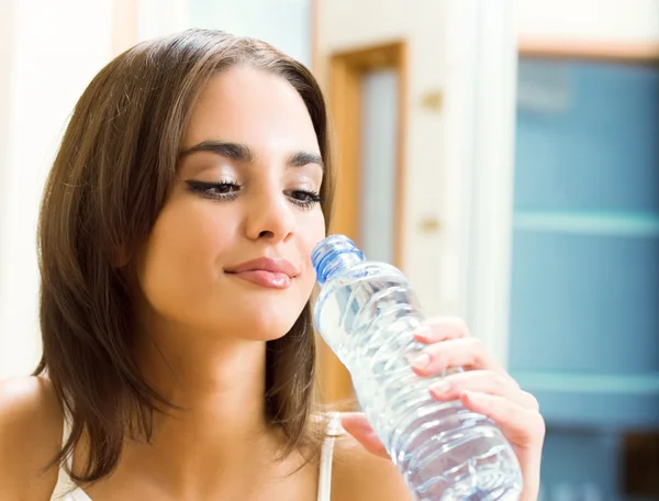 Молодая женщина пьет воду в помещении — стоковое фото