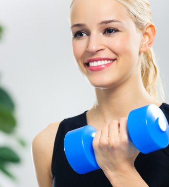 Genç mutlu gülümseyen kadın kapalı dumbbells ile