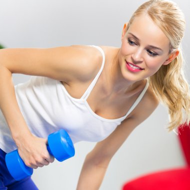 Genç mutlu gülümseyen kadın kapalı dumbbells ile