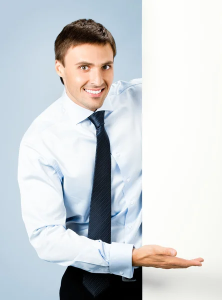 Geschäftsmann zeigt leeres Schild, über blau — Stockfoto