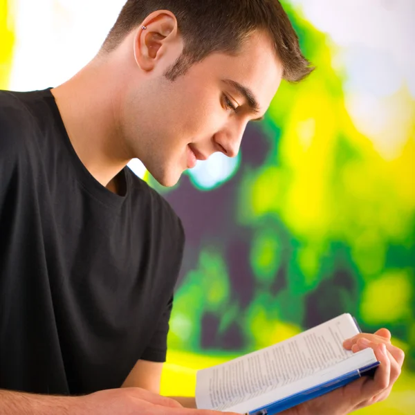 Jeune homme heureux lisant le livre ou le manuel, extérieur — Photo