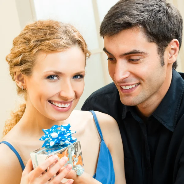Fröhliches verliebtes Paar mit Geschenken, drinnen — Stockfoto