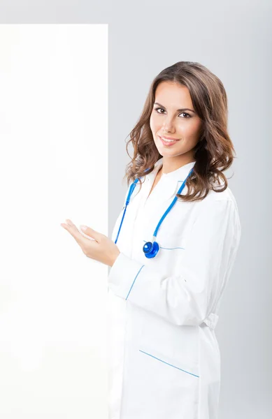 Médica feminina mostrando tabuleta, sobre cinza — Fotografia de Stock