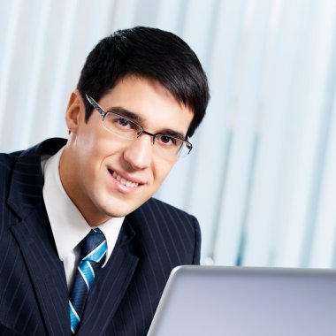 laptop ile ofiste çalışan işadamı gülümseyen