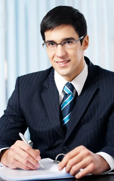 Portrait of writing smiling businessman working at office — Stock Photo, Image