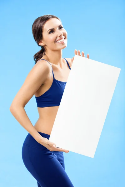 Frau in Fitnessbekleidung zeigt Schild, über blau — Stockfoto