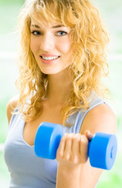 Genç mutlu gülümseyen kadın kapalı dumbbells ile