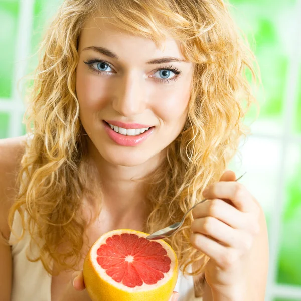 Vrolijke blonde vrouw eten grapefruit — Stockfoto