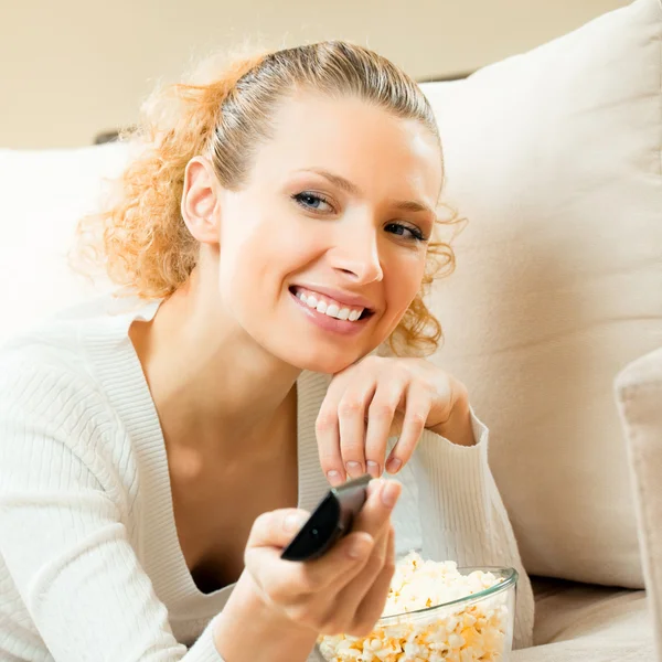 Usmívající se žena sleduje tv doma — Stock fotografie