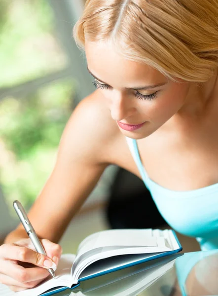 Junge Frau lernt mit Notizbuch, drinnen — Stockfoto