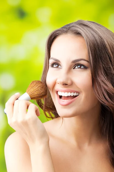 Smiling woman with make up brush, outdoor — Stock Photo, Image