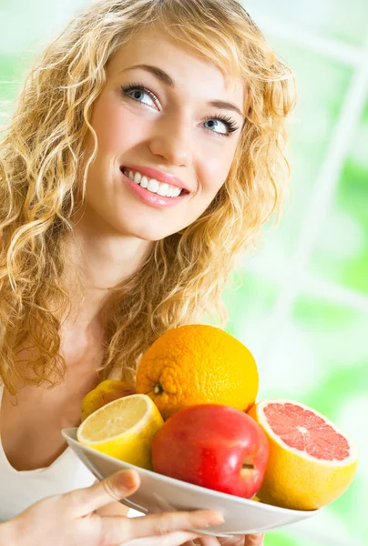 Vrolijke lachende blonde vrouw met vruchten — Stockfoto