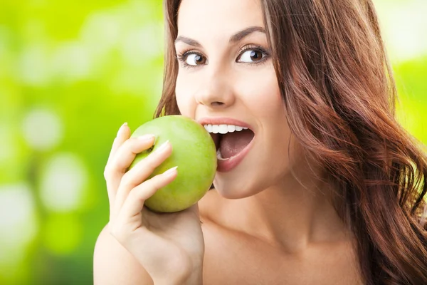 Mujer joven comiendo manzana, al aire libre — Foto de Stock