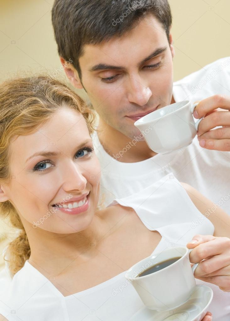 Cheerful couple with cups of coffee, indoor