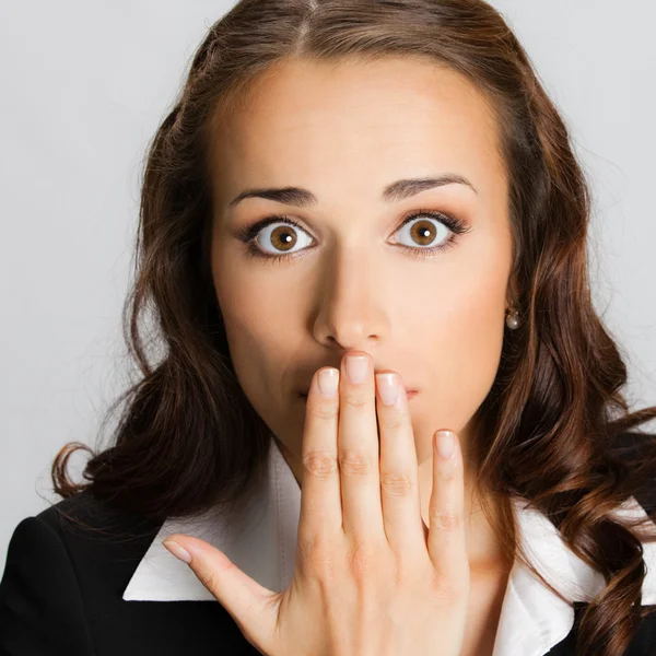 Businesswoman covering mouth, over gray — Stock Photo, Image