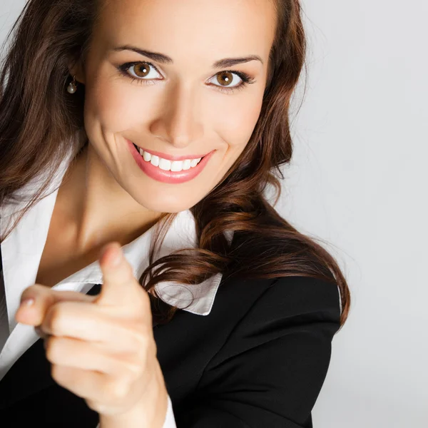 Mujer de negocios señalando con el dedo al espectador, sobre gris — Foto de Stock