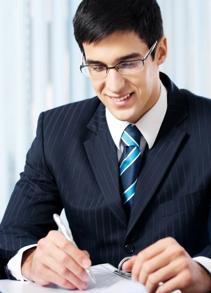 Portrait of writing smiling businessman working at office — Stock Photo, Image