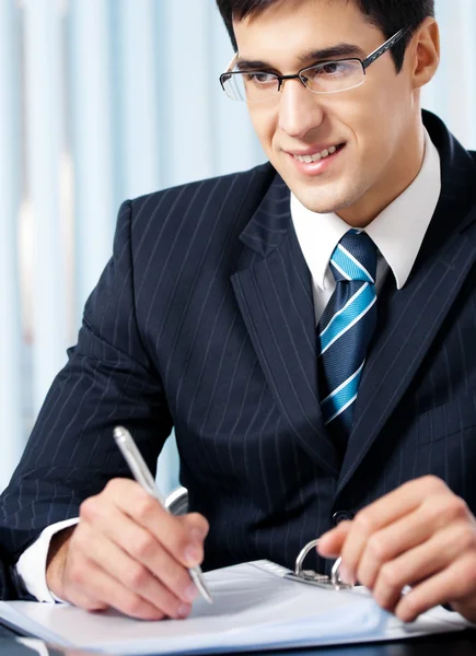 Porträt eines schreibenden lächelnden Geschäftsmannes im Büro — Stockfoto