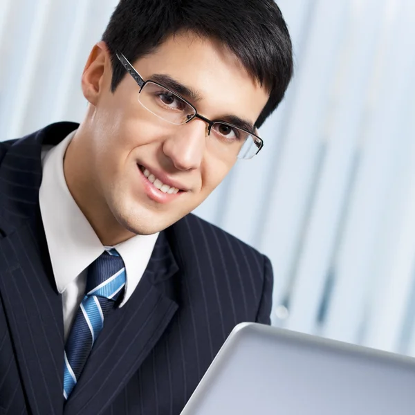Hombre de negocios sonriente trabajando con el ordenador portátil en la oficina —  Fotos de Stock