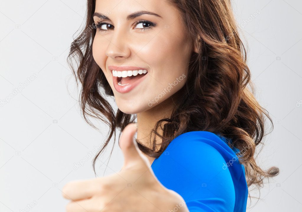 Young woman with thumbs up gesture, over grey