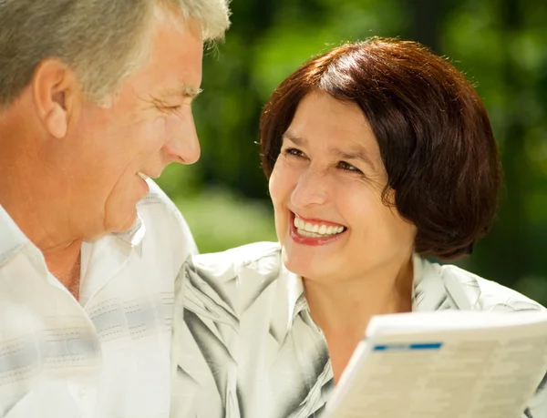 Happy senior couple reading outdoors — Stock Photo, Image