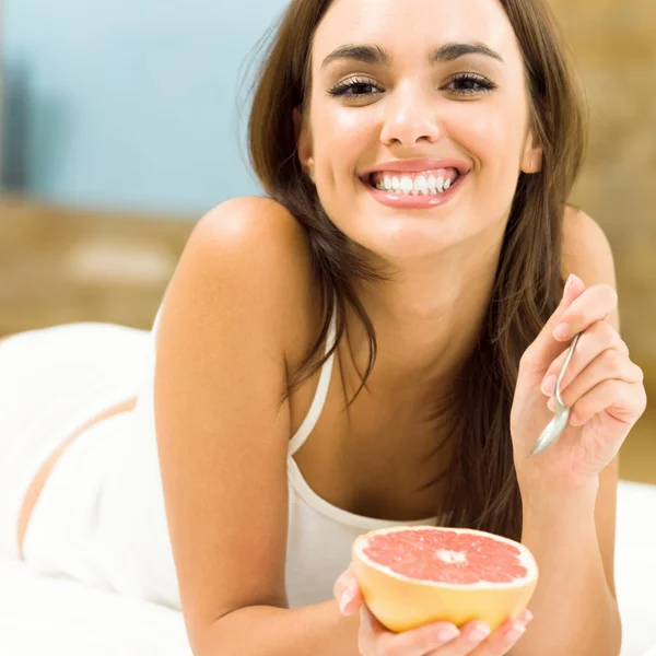 Portarit mladá žena doma jíst grapefruit — Stock fotografie
