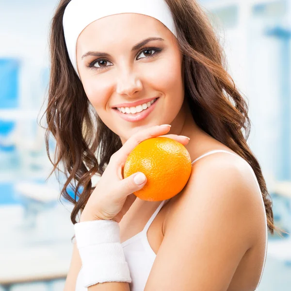 Woman with orange, at fitness center — Stock Photo, Image