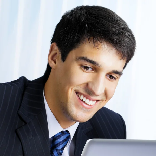 Hombre de negocios sonriente trabajando con el ordenador portátil en la oficina —  Fotos de Stock