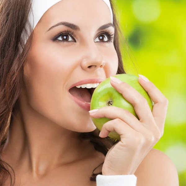 Woman in fitness wear with apple, outdoors — Stock Photo, Image