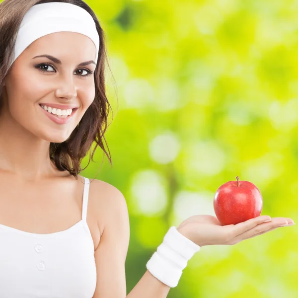 Mujer en ropa de fitness con manzana, al aire libre —  Fotos de Stock