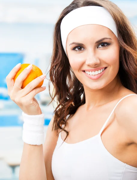 Woman with orange, at fitness center — Stock Photo, Image