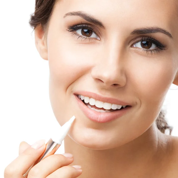 Smiling woman applying concealer on face, isolated — Stock Photo, Image