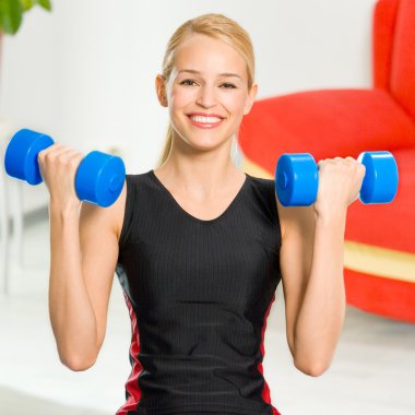 Genç mutlu gülümseyen kadın kapalı dumbbells ile