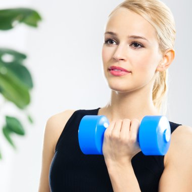 Genç mutlu gülümseyen kadın kapalı dumbbells ile