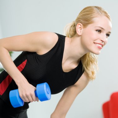 Genç mutlu gülümseyen kadın kapalı dumbbells ile