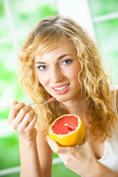 Vrolijke blonde vrouw eten grapefruit — Stockfoto