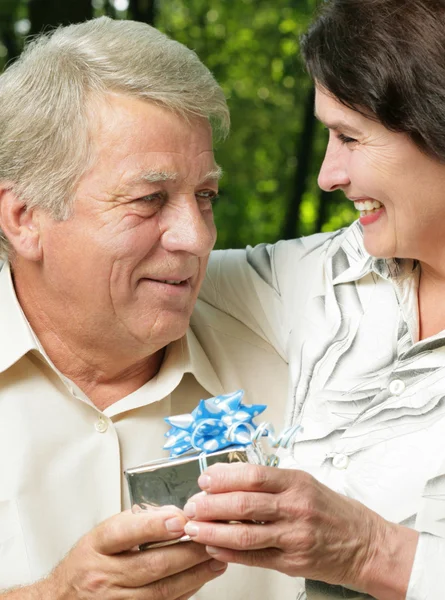 Äldre par omfattar i park med gåva — Stockfoto