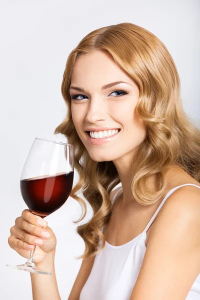 Jonge gelukkig vrouw met glas rode wijn, op grijs — Stockfoto