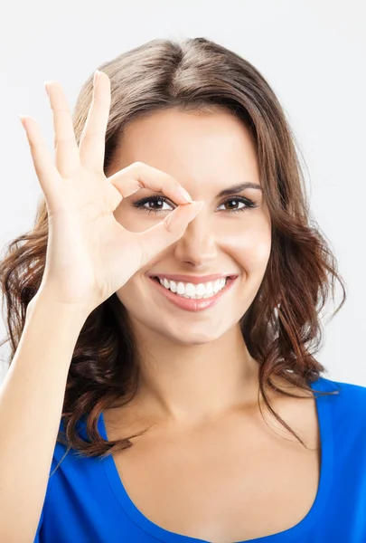 Young woman showing okay gesture, over grey — Stock Photo, Image