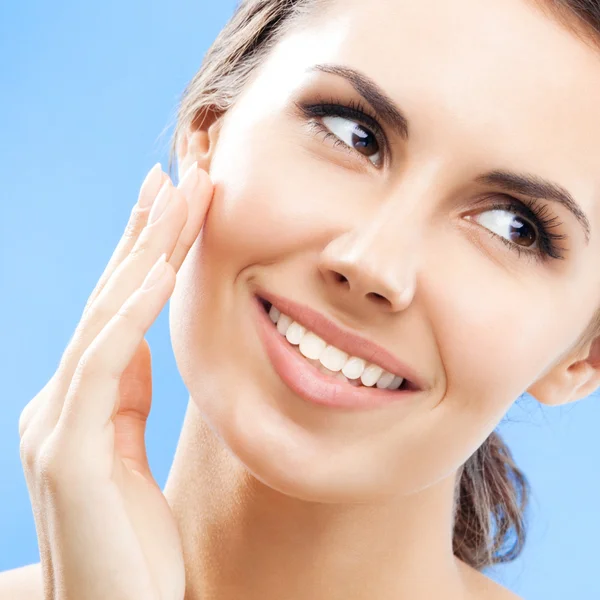 Woman touching skin or applying cream, over blue — Stock Photo, Image