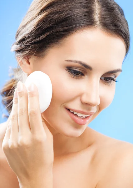 Young woman cleaning skin by cotton pad, over blue — Stock Photo, Image