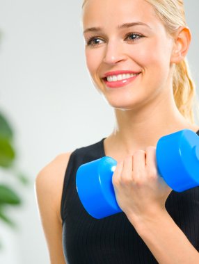 Genç mutlu gülümseyen kadın kapalı dumbbells ile