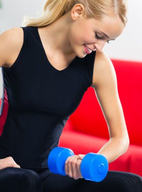Genç mutlu gülümseyen kadın kapalı dumbbells ile