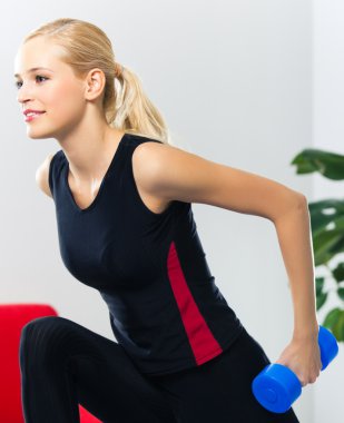 Genç mutlu gülümseyen kadın kapalı dumbbells ile