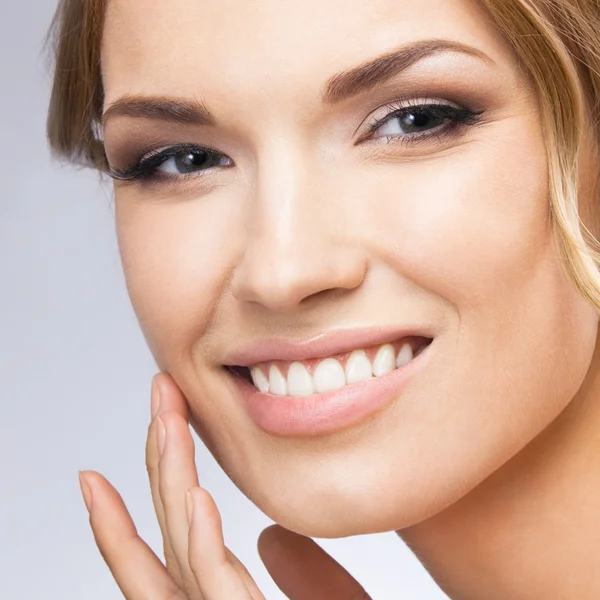 Woman touching skin or applying cream, on grey — Stock Photo, Image