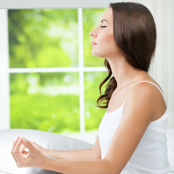 Jovem mulher bonita meditando, dentro de casa — Fotografia de Stock