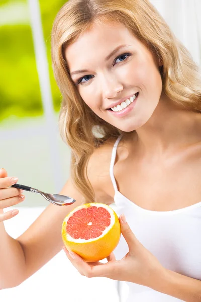 Lachende vrouw eten grapefruit thuis — Stockfoto