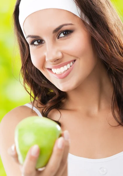 Woman in fitness wear with apple, outdoors — Stock Photo, Image