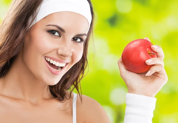 Mulher em desgaste fitness com maçã, ao ar livre — Fotografia de Stock